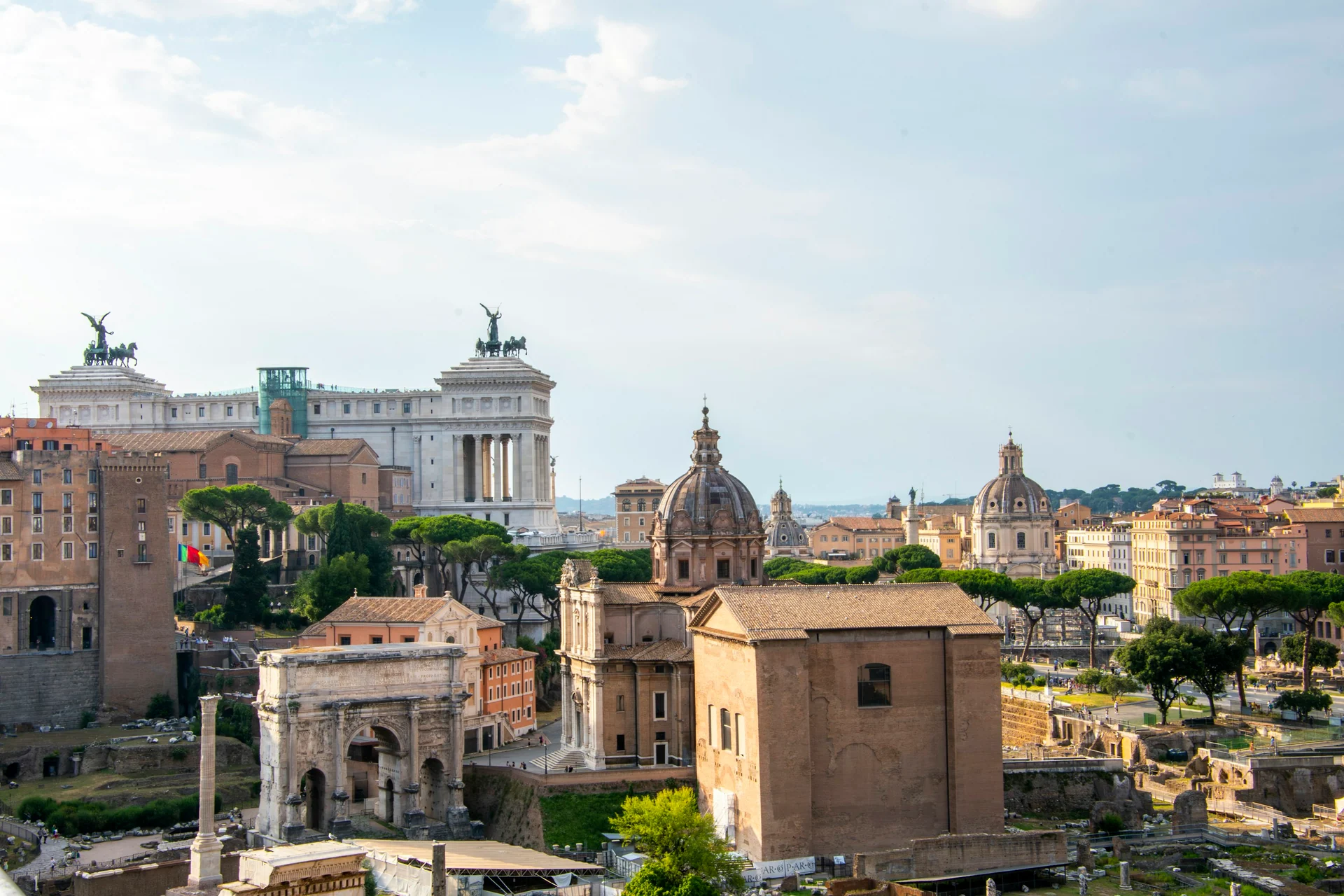 Sunlit Roman Forum ruins, church domes and umbrella pines seen from above